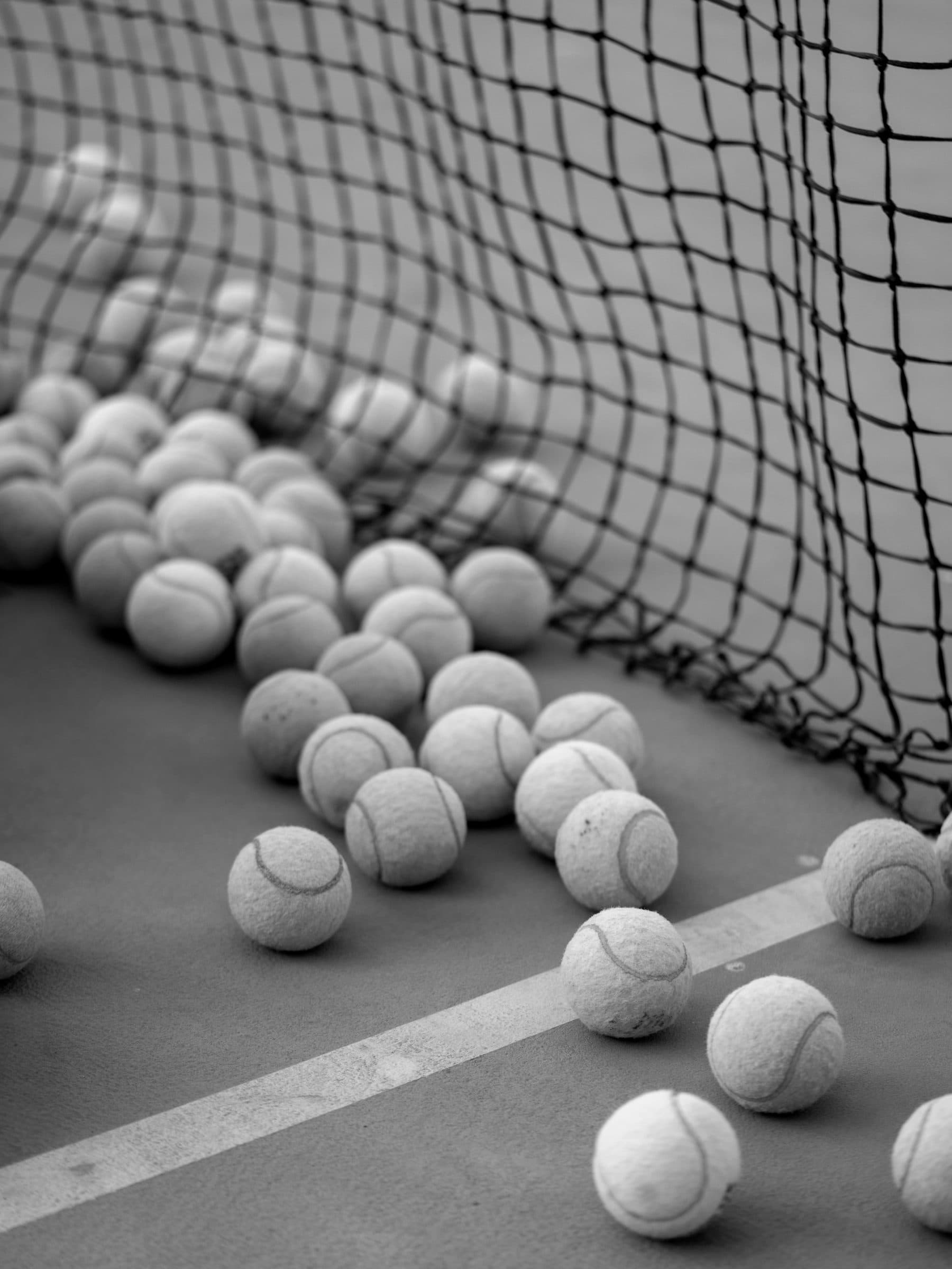 Viele Bälle liegen am Netz auf dem Court